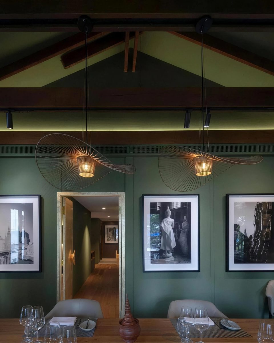 The smaller private room: two woven pendant lamps over the table and black and white photographs on green walls