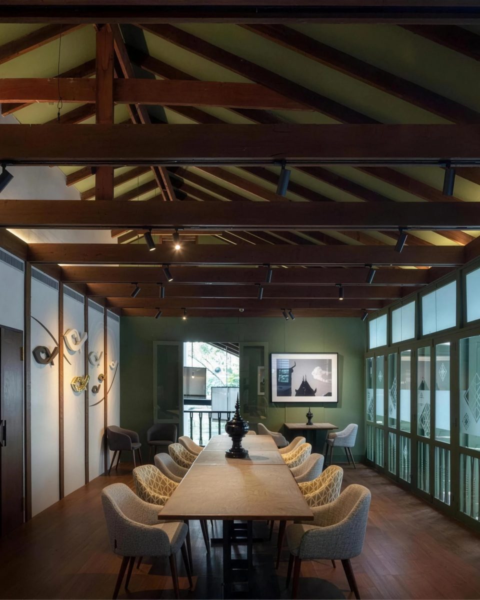 The larger private room: one long table under the timber truss, green walls and tall windows