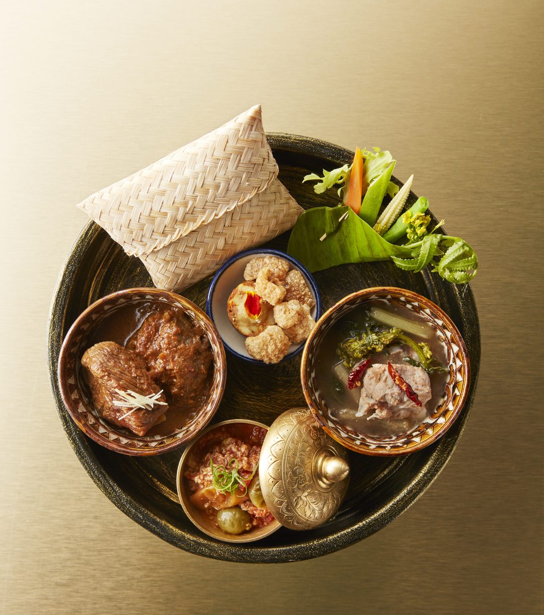 A samrub on a round tray: small bowls around a woven rice basket